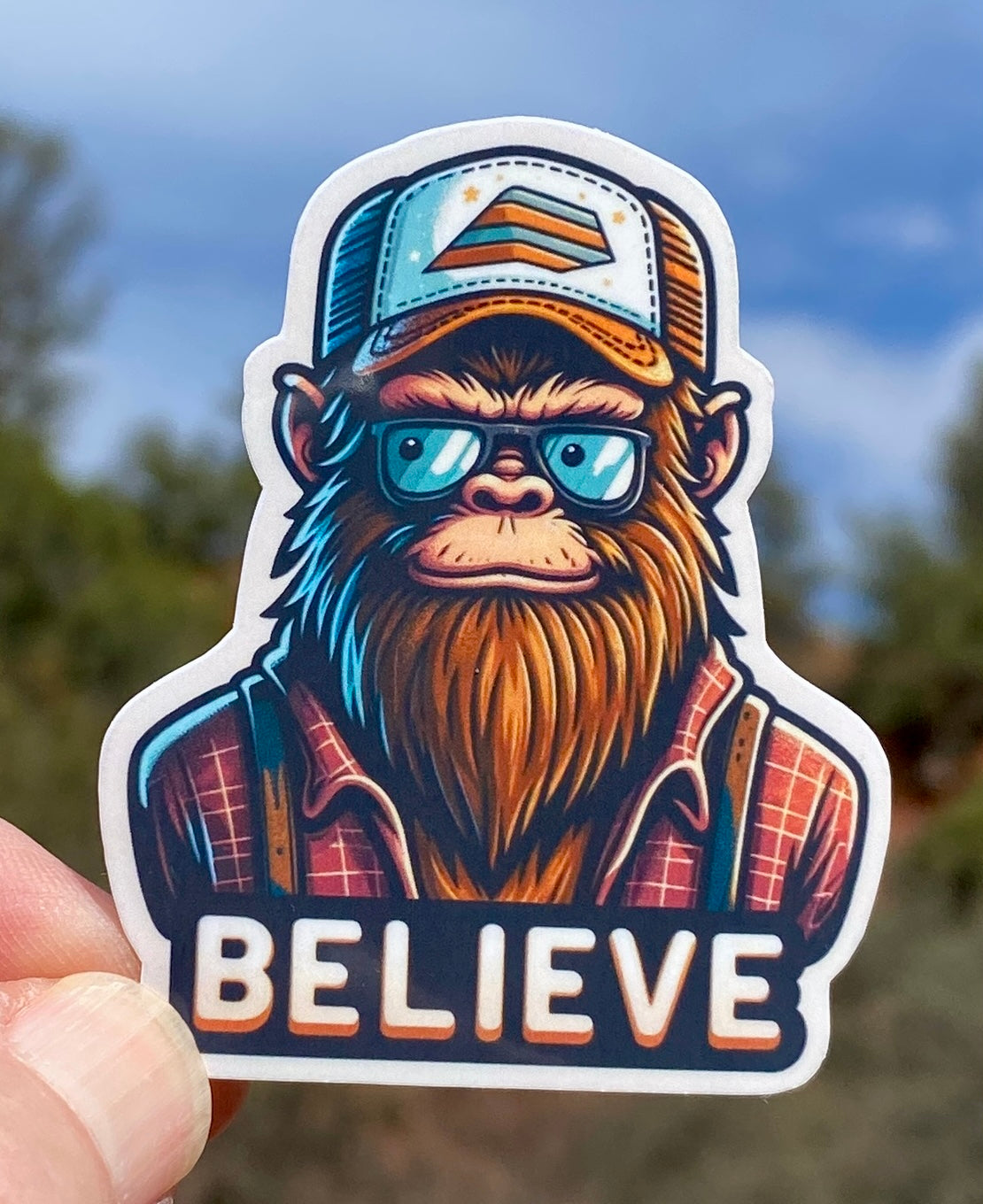 Bigfoot wearing flannel and a trucker hat that says Believe Sticker, Believe, sticker, flannel, trucker hat,Bigfoot, Sasquatch, Cryptid, fun